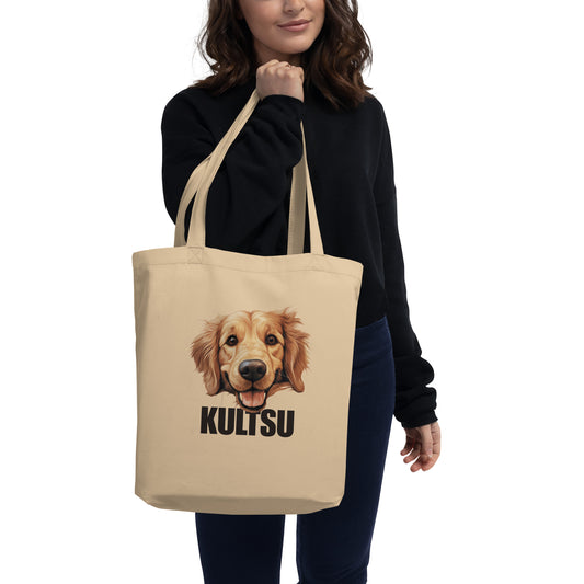 Nainen pitelee olallaan isoa kangaskassia, jossa kultaisennoutajan kuva ja ruskea teksti "kultsu".