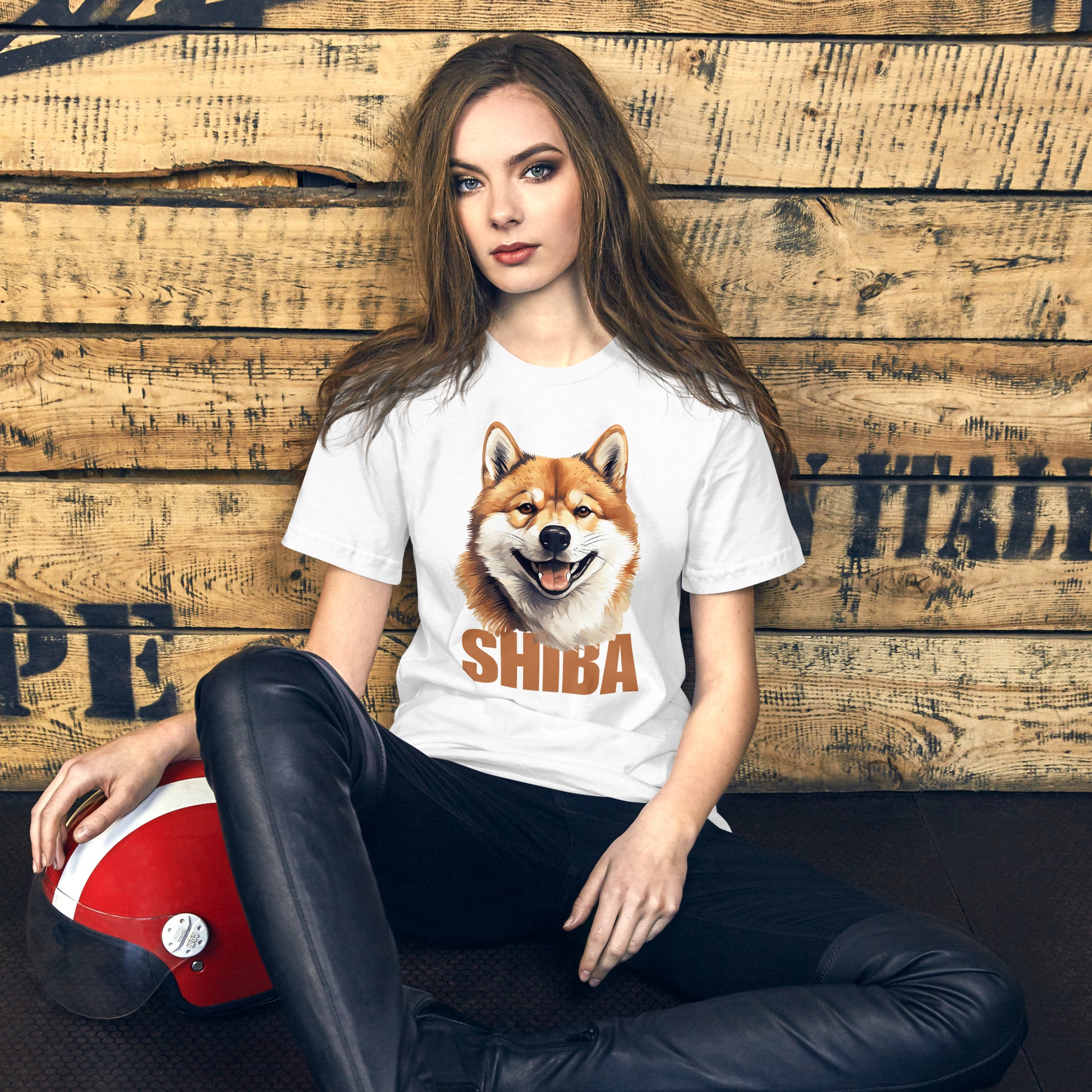 Nainen istuu puuseinää vasten, yllään valkoinen t-paita, jossa on Shiba Inu -koiran kuva ja sana Shiba