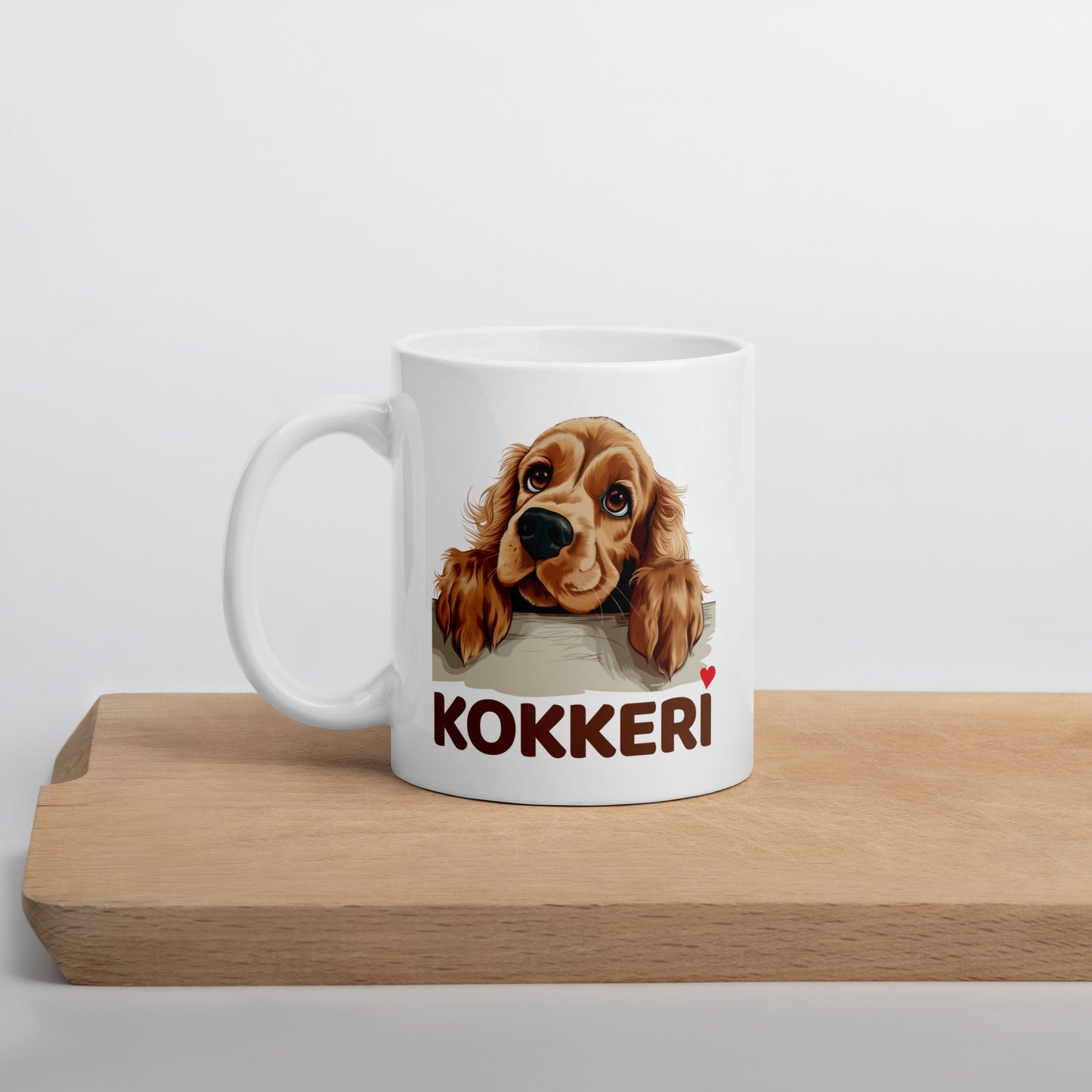 Valkoinen cockerspanieli muki puisen leikkuulaudan päällä.