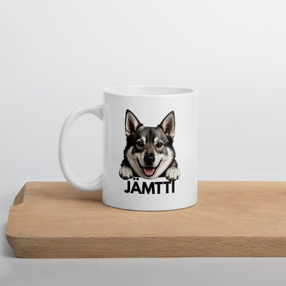 Valkoinen jämtlanninpystykorva-aiheinen muki "jämtti"-tekstillä, puisen laudan päällä kuvattuna.