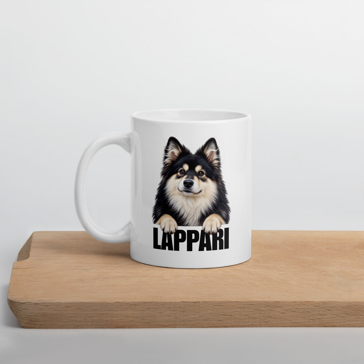 Suomenlapinkoira-aiheinen valkoinen muki puisen leikkuulaudan päällä.