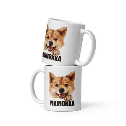 Kaksi valkoista mukia päällekkäin, joissa iloisen suomenpystykorvan kuva ja musta teksti "pikinokka".