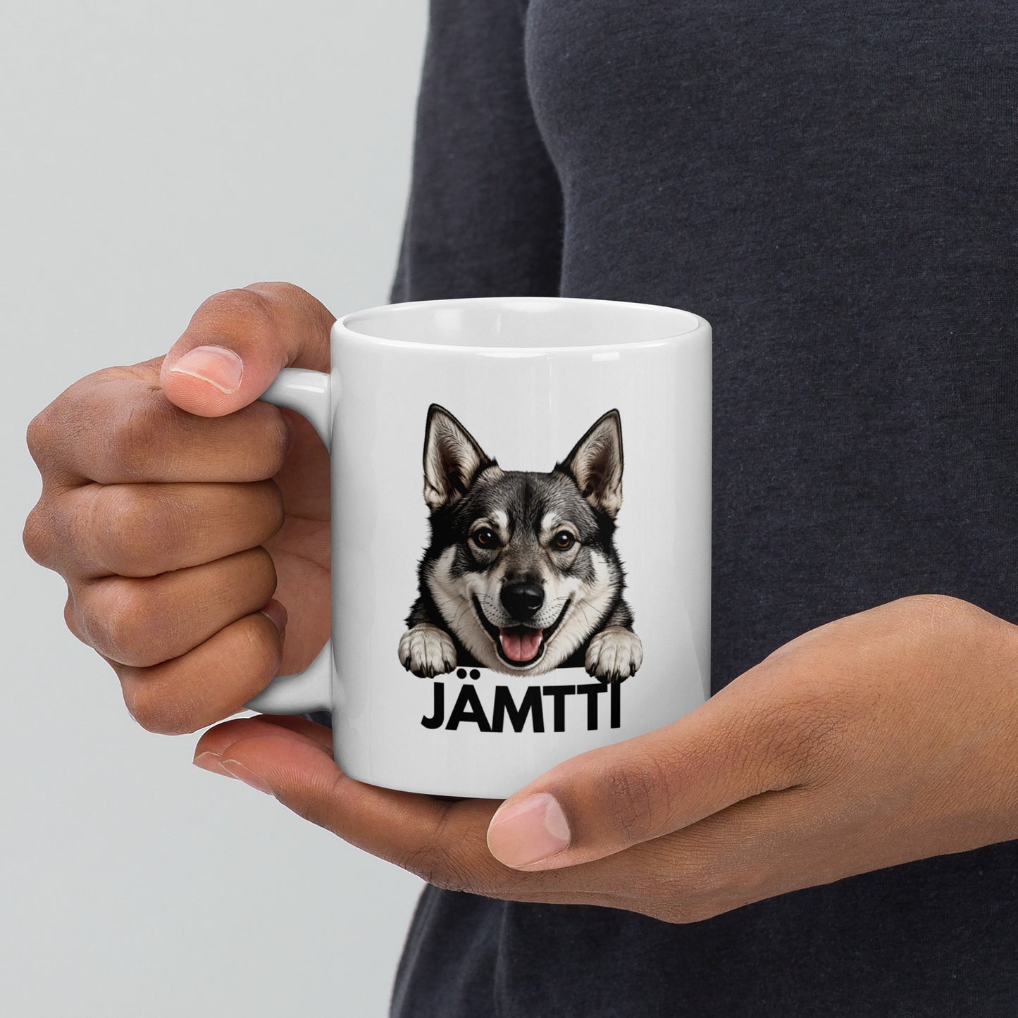 Mies pitelee käsissään jämtlanninpystykorva mukia, jossa jämttin kuva ja tumma teksti "jämtti".