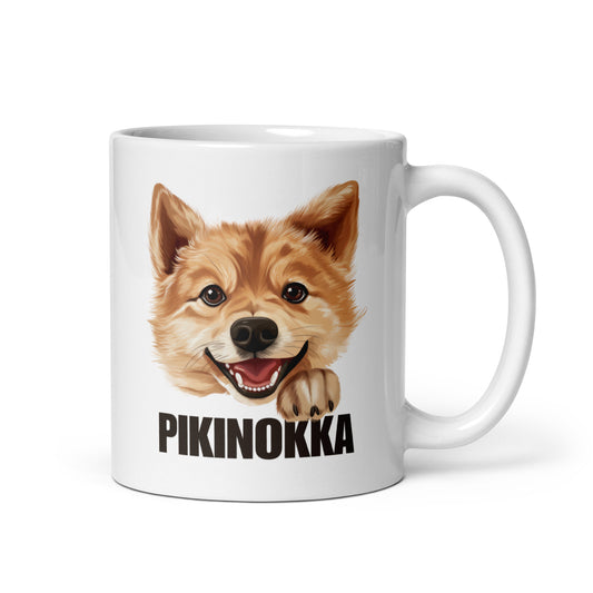 Lähikuva kiiltävänvalkoisesta mukista, jossa suomenpystykorvan kuva ja tumma teksti "pikinokka".