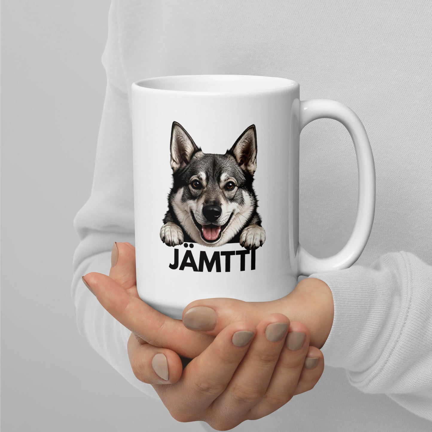 Isompi valkoinen jämtlanninpystykorva muki henkilön käsissä.