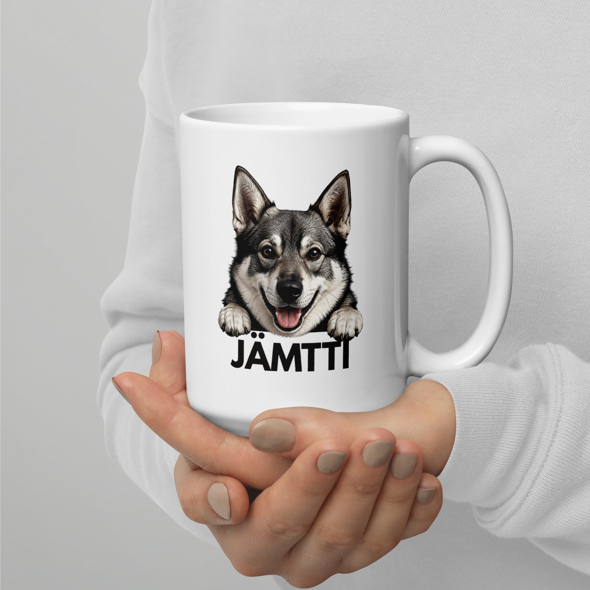 Isompi valkoinen jämtlanninpystykorva muki henkilön käsissä.