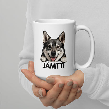 Isompi valkoinen jämtlanninpystykorva muki henkilön käsissä.