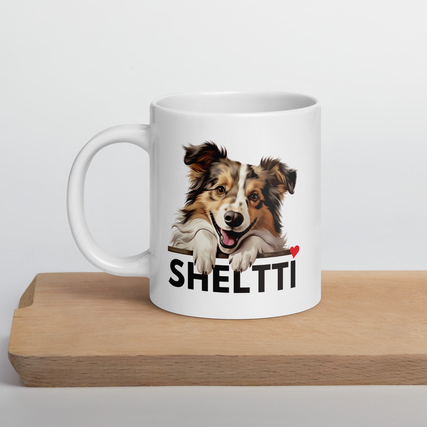 Kiiltävänvalkoinen muki, jossa shetlanninlammaskoiran kuva ja teksti "sheltti" sydämellä varustettuna.