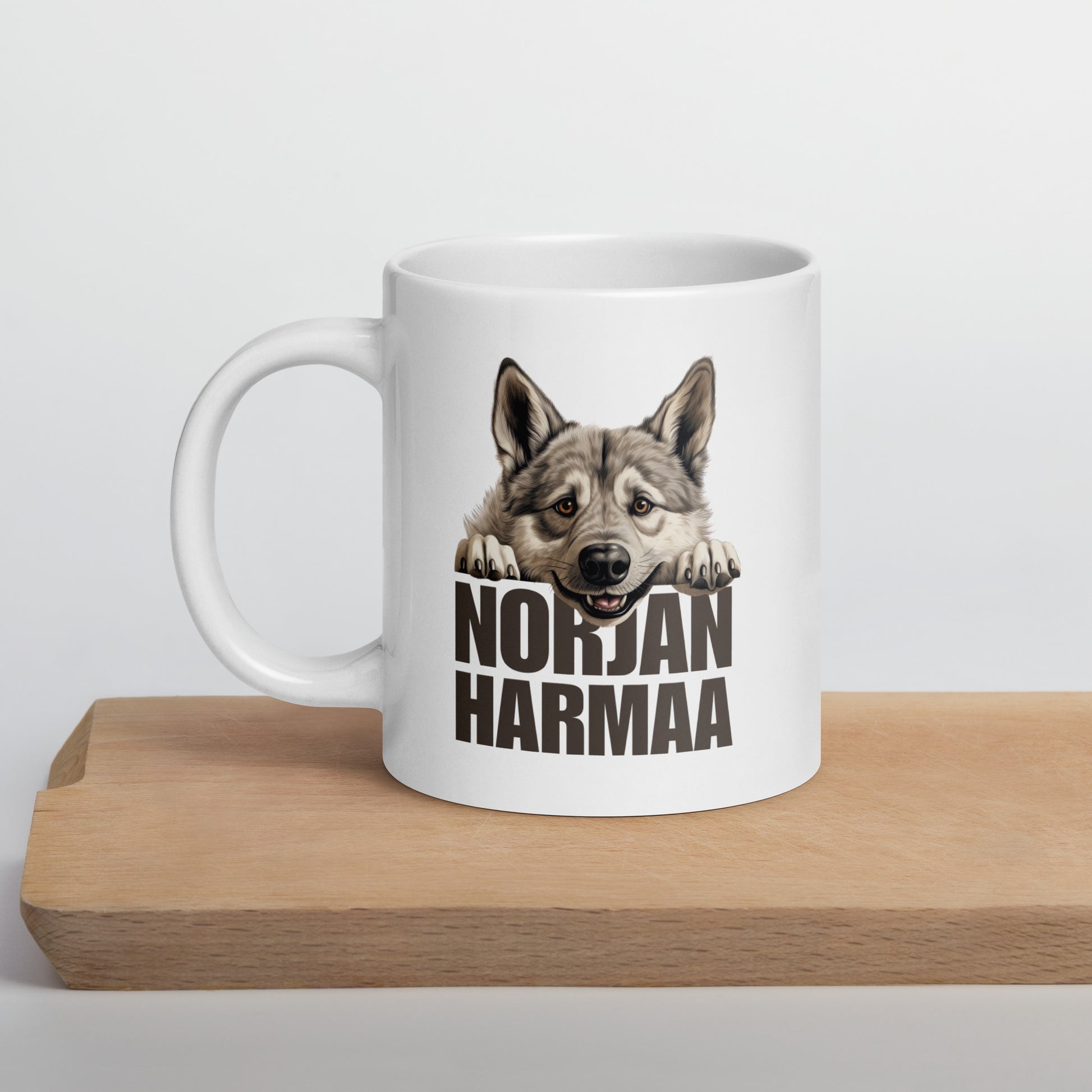 Leikkuulaudan päällä valkoinen muki, jossa harmaan norjanhirvikoiran kuva ja teksti "norjanharmaa".