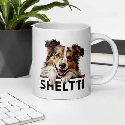 Työpöydällä valkoinen muki, jossa shetlanninlammaskoiran kuva ja teksti "sheltti" sydämmellä varustettuna. 