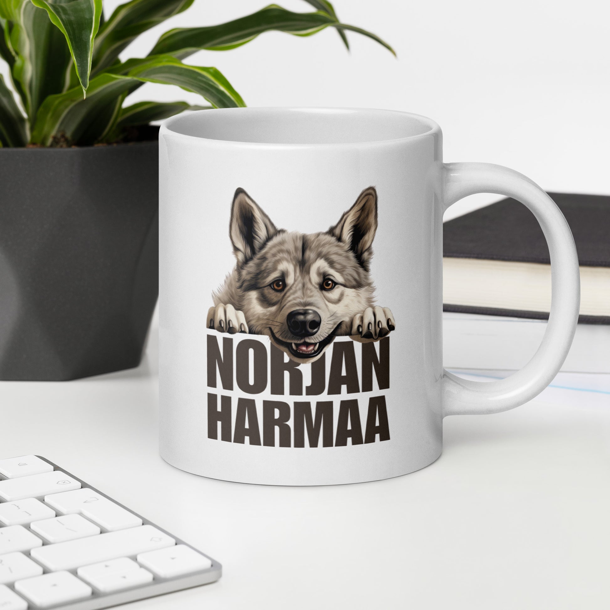 Valkoinen muki pöydällä, jossa harmaan hirvikoiran kuva ja teksti "norjanharmaa".